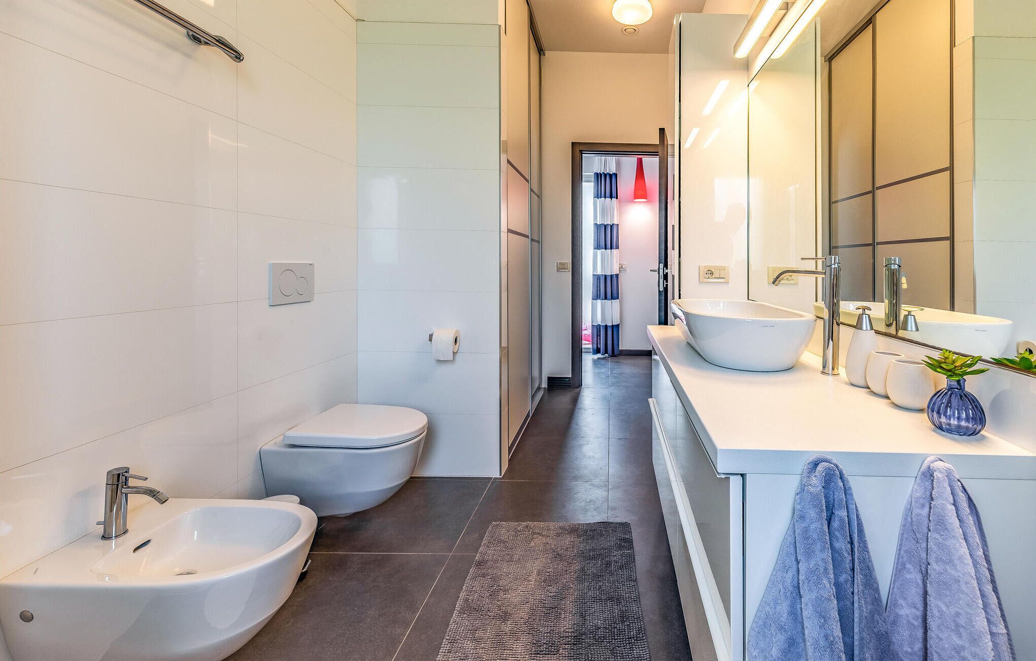 A modern bathroom with a bidet, toilet, and sink.