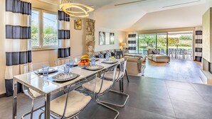 A modern dining area with a long table, clear chairs, and a stone accent wall. - Awesome home in Banjole (Banjole)