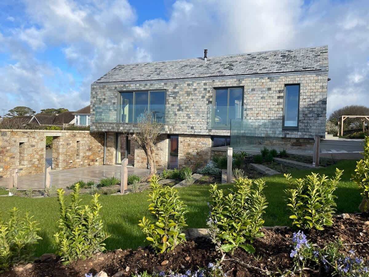 A modern house with a stone facade, large windows, and a well-maintained garden.