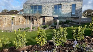 Ein modernes Haus mit einer Steinfassade, großen Fenstern und einem gepflegten Garten.