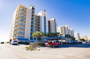 Un hôtel à plusieurs étages doté de balcons, d’un parking et de palmiers.