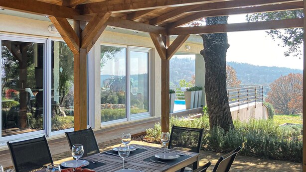 An outdoor dining area with a table set for two, large windows, and a view of a pool and landscape. - Luxurious home in Rovinj (Rovinj)