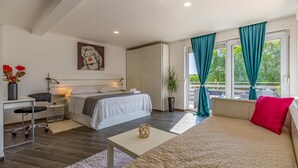 A modern bedroom with a bed, a desk, a chair, a plant, and a view of the outdoors. - Luxurious home in Rovinj (Rovinj)
