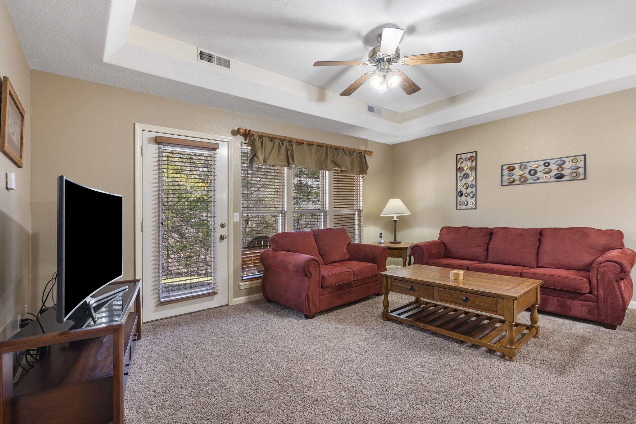A living room with a TV, two sofas, a coffee table, and a ceiling fan.
