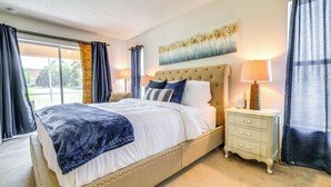 Ein Schlafzimmer mit Bett, Nachttischlampen, einem Nachttisch und einem Deckenventilator.