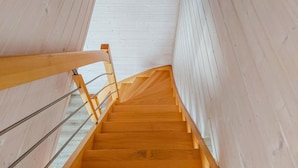 A wooden staircase with a metal handrail, leading upwards.