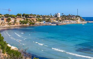 Un pueblo costero con un puerto deportivo, aguas azules cristalinas y edificios a lo largo de la costa.