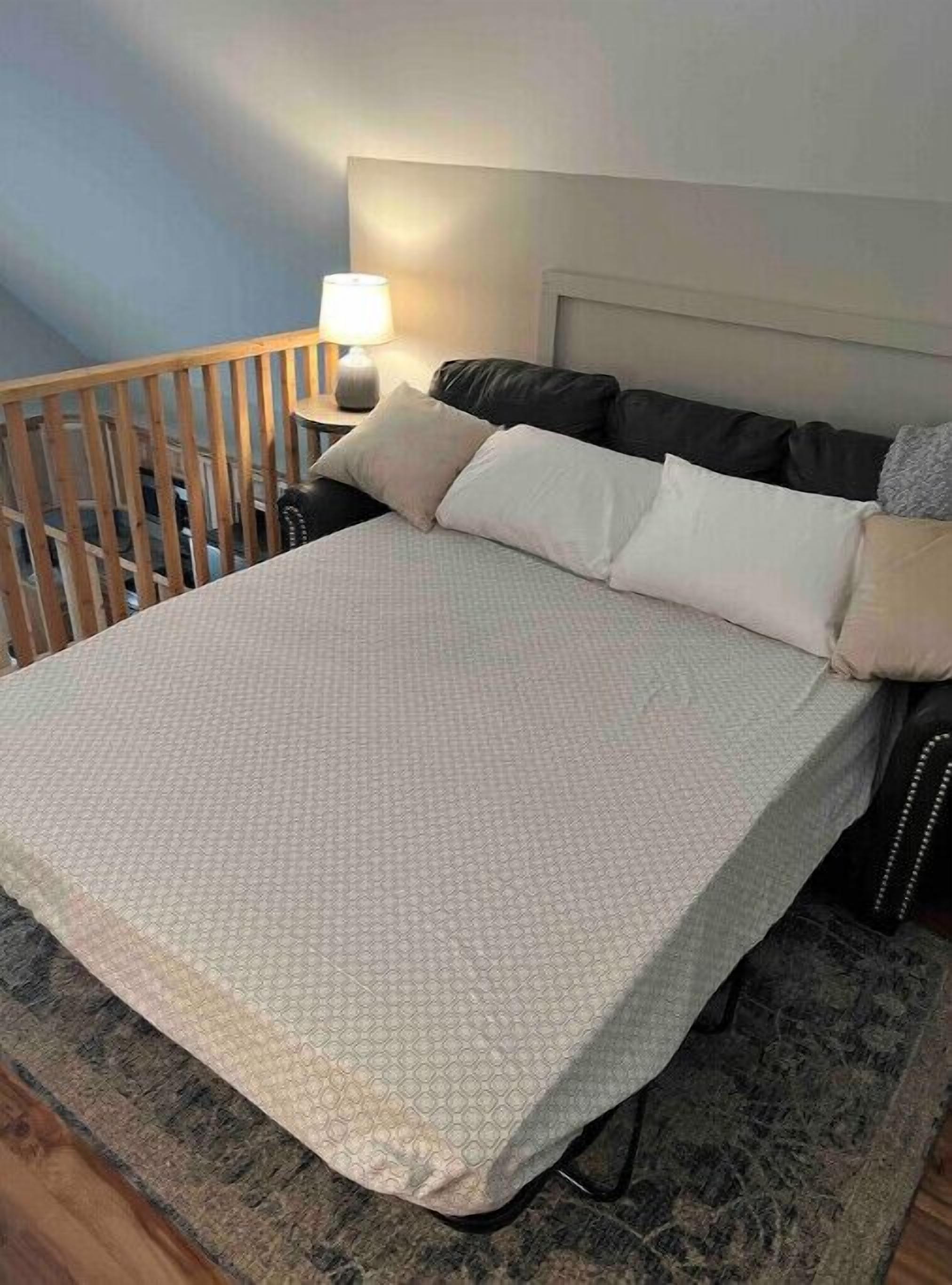 Un dormitorio con cama, mesita de noche, lámpara y baranda de madera.