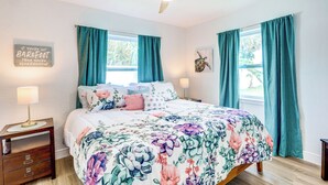 A bedroom with a bed, two nightstands, a ceiling fan, and teal curtains. - Pet-Friendly Cocoa Beach Home: Walk to Beach! (Cocoa Beach)