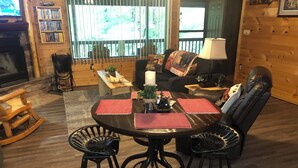 A cozy living room with a round table, two chairs, a sofa, and a fireplace.