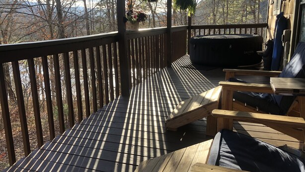 A wooden deck with a railing, outdoor seating, and hanging plants.