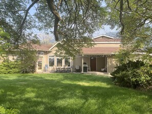 A house with a covered patio, a barbecue area, and a lawn.