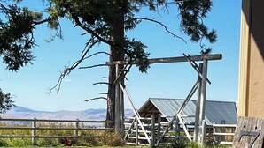 A wooden sign with numbers, a fenced area, a tree, and a building in the background. - Comfortable Montana Country Home for Family Getaways (Arlee)