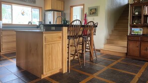 A kitchen with wooden cabinets, a central island, and a dining area with chairs. - Comfortable Montana Country Home for Family Getaways (Arlee)