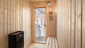 Un couloir intérieur en bois, avec une poubelle noire sur laquelle est écrit « helo » et une horloge fixée au mur.