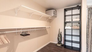 Un dressing avec des étagères, une tringle à vêtements et un aspirateur.