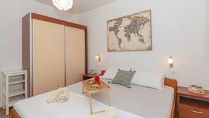 A hotel room with a bed, a wooden nightstand, a desk, a map artwork on the wall, and a wardrobe. - 3 bedroom beautiful home in Rogoznica (Rogoznica)
