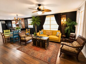 A living room with a sofa, chairs, a coffee table, a ceiling fan, and a fireplace. - Cuban Vibe Home  
BBQ, pool, 3Bd near Cruise-Downtown-Ybor-Sleeps 8 (Tampa)