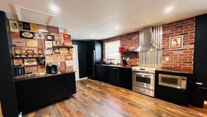 Una cocina con pared de ladrillo, suelo de madera, extractor de acero inoxidable y microondas.