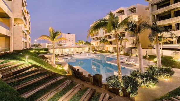 Ein Resort mit Schwimmbad, Palmen und modernen Gebäuden.