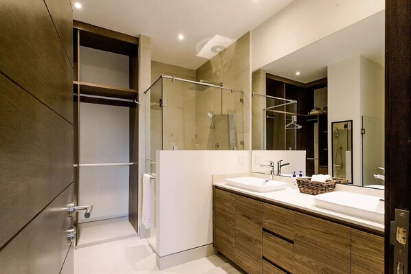 A modern bathroom with a walk-in shower, a large mirror, and a wooden vanity with a sink.