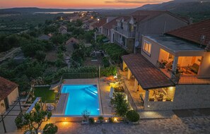 Un quartier résidentiel doté d’une piscine, d’un jardin bien entretenu et de maisons aux toits recouverts de tuiles rouges.