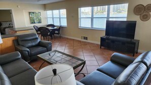 Relax in a serene space with a sofa, armchairs, and a TV, offering a view of the water.