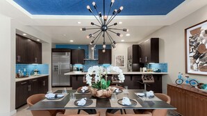 Una cucina moderna con mobili scuri, un frigorifero in acciaio inossidabile e un pannello di fondo blu.
