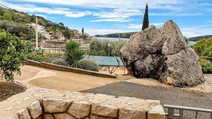 A rocky landscape with a large boulder, a paved area with a metal railing, and a view of a town with buildings and a body of water in the distance. - 2 bedroom stunning apartment in Molunat (Molunat)