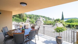 A balcony with a table and chairs, overlooking a scenic landscape with trees and a body of water. - 2 bedroom stunning apartment in Molunat (Molunat)