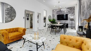 Ett modernt vardagsrum med en soffa, ett soffbord och en matplats med stolar och ett bord.