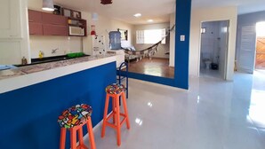 A modern kitchen with a blue accent wall, two colorful stools, and a central island. - Porto de Galinhas Maracaipe, close to the sea. (Ipojuca)