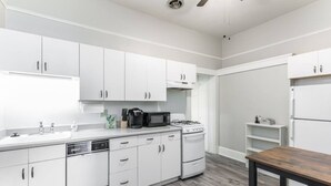 A modern kitchen with white cabinets, a microwave, a gas stove, and a wooden dining table. - Historic Jostaad Home! (Tucson)