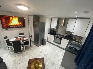 A modern kitchen with a dining area, a flat-screen TV, and a fireplace.