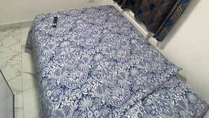 Une chambre à coucher avec un lit, un téléviseur fixé au mur et des rideaux à motifs.
