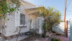 A white house with a porch, a small garden with flowers, and a wooden fence.