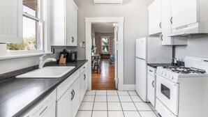 Una cucina moderna con mobili bianchi, un piano di lavoro nero, un lavello, un fornello e un forno.