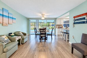 A spacious living room with a dining area, a kitchen, and a view of the outdoors. - Cozy Oasis Screened Pool Picturesque Water Canal Views! (Port Richey)
