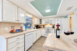 A modern kitchen with white cabinetry, a built-in oven, and a dining area with a table set for two. - Cozy Oasis Screened Pool Picturesque Water Canal Views! (Port Richey)