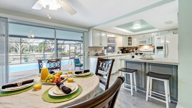 Una cocina moderna con comedor, ventanas amplias y vistas a una piscina.