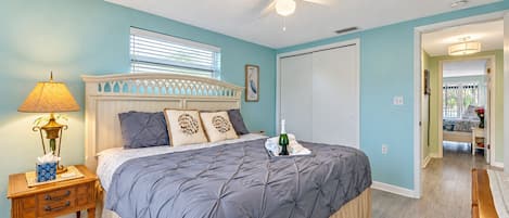 Une chambre à coucher avec un lit, une table de chevet, une lampe et un ventilateur de plafond.