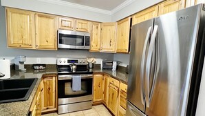 A modern kitchen with wooden cabinets, stainless steel appliances including a refrigerator, microwave, and oven, and a granite countertop. - Adventure Awaits! Hike, ski, bike, golf & relax! (Beech Mountain)