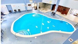 An indoor swimming pool with a curved edge, surrounded by seating areas and a stone wall. - Adventure Awaits! Hike, ski, bike, golf & relax! (Beech Mountain)
