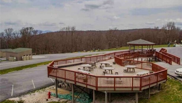 A covered outdoor area with tables and chairs, a gazebo, and a view of a forested area. - Adventure Awaits! Hike, ski, bike, golf & relax! (Beech Mountain)
