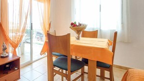 A dining area with a table set for two, a vase with flowers, and a view of the outside through large windows. - 2 bedroom beach front apartment in Bellreguard (Bellreguard)