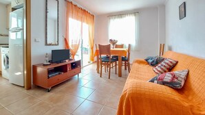 A compact living space with a kitchenette, a dining area, and a sofa with patterned cushions. - 2 bedroom beach front apartment in Bellreguard (Bellreguard)
