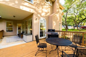 Eine überdachte Terrasse mit Holzdeck, Sitzgelegenheiten im Freien und einem Grill.