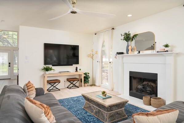 Ein modernes Wohnzimmer mit Flachbildfernseher, Kamin, Sofa und Couchtisch.