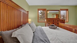 A bedroom with a bed, wooden headboard, dresser, and a ceiling fan.