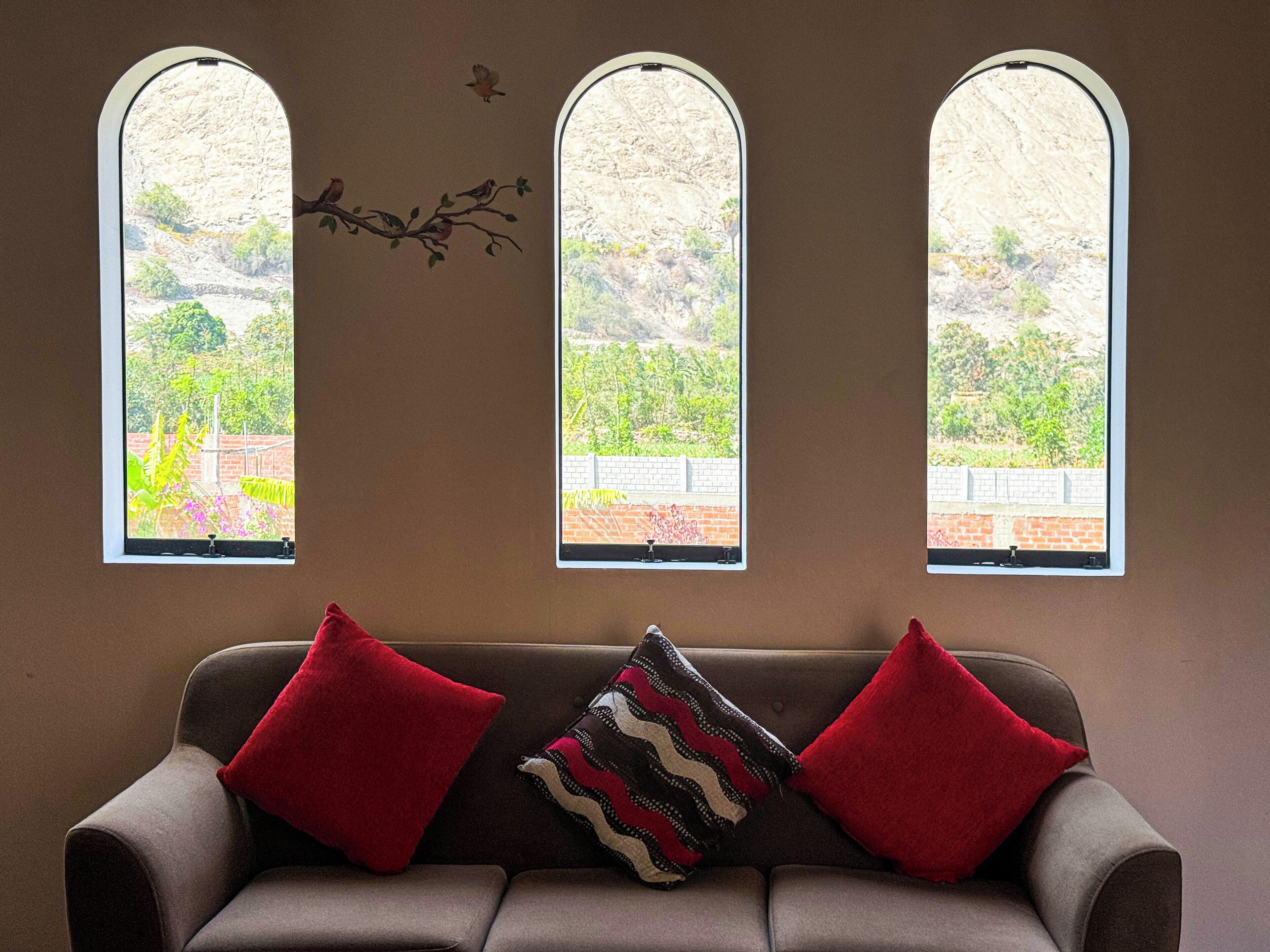 Una habitación con un sofá y tres ventanas de arco.